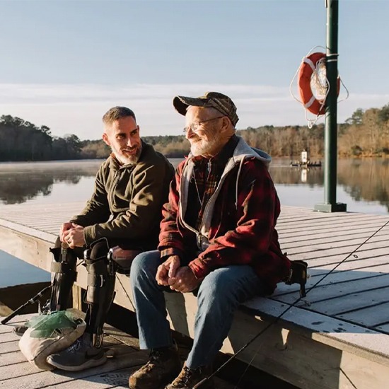 A patient wearing a C-Brace is sitting on a boat with an old man in New York and New Jersey