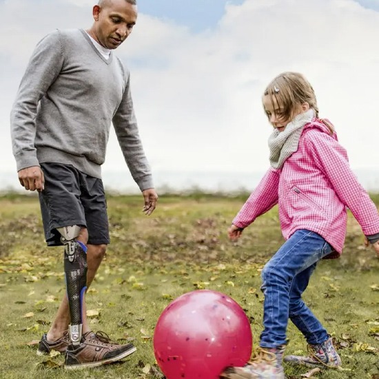 A father wearing a C-Brace playing football with his daughter in New York and New Jersey